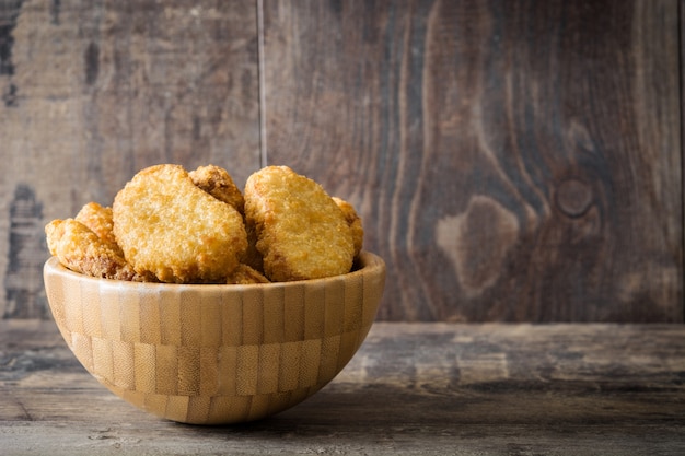 Gebakken kipnuggets in kom op houten tafel