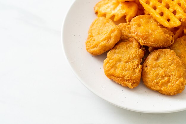 Gebakken kipnuggets met gebakken aardappelen op plaat potatoes