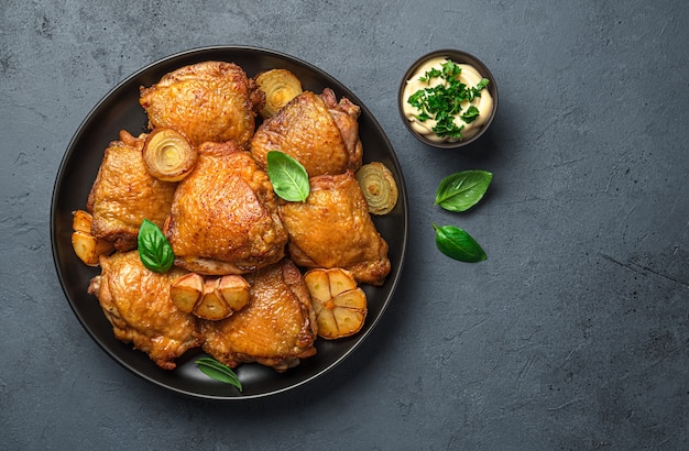 Gebakken kippendijen met verse basilicum en saus op een grafietachtergrond bovenaanzicht kopieerruimte