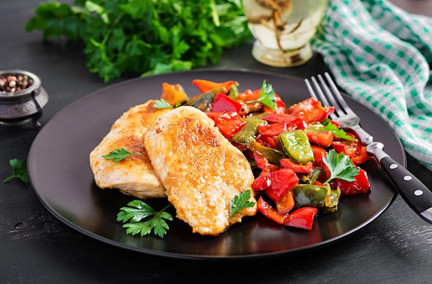 Gebakken kippenfilet en zoete peper op een zwart bord