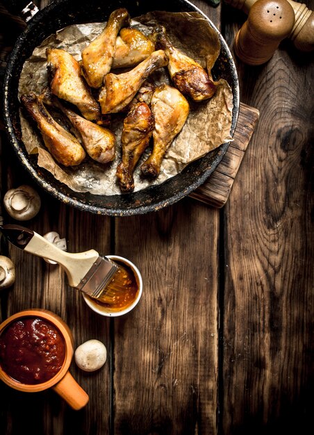 Gebakken kippenpoten met tomatensaus. Op een houten tafel.