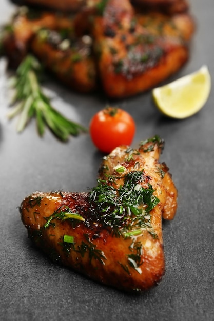 Gebakken kippenvleugels met tomaten en rozemarijn op grijze achtergrond