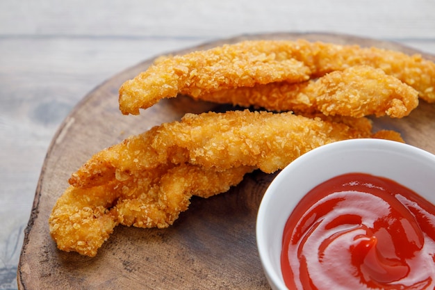 Gebakken kipreepjes met tomatensaus op houten tafel