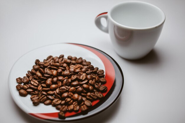 Gebakken koffiebonen en witte kop geïsoleerd op een witte achtergrond vintage fotoverwerking