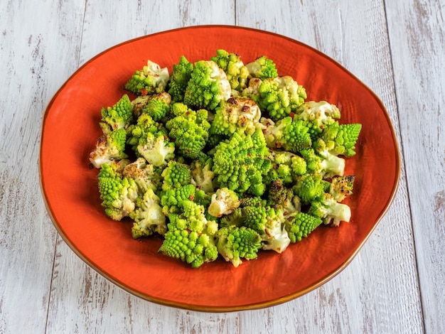 Gebakken koolromanesco met kruiden op een oranje plaat