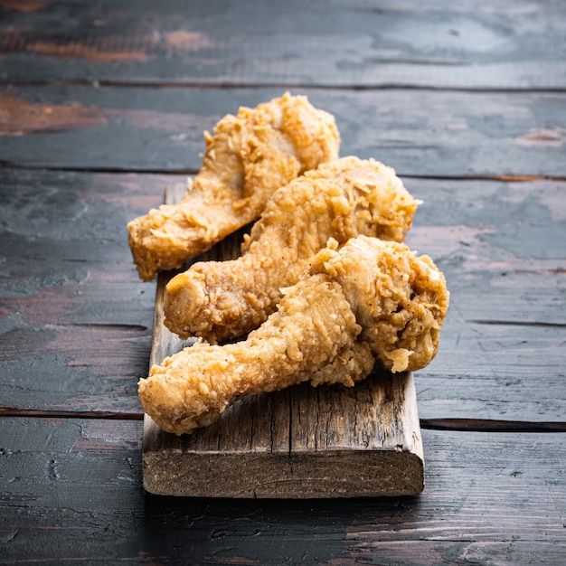 Gebakken krokante kippenpoten, drumstickdelen op donkere houten tafel.