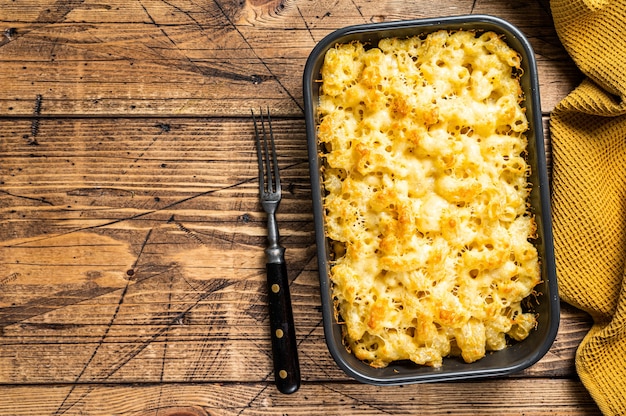 Gebakken Mac en kaas Amerikaans gerecht met cheddarsaus. Houten achtergrond. Bovenaanzicht. Kopieer ruimte.