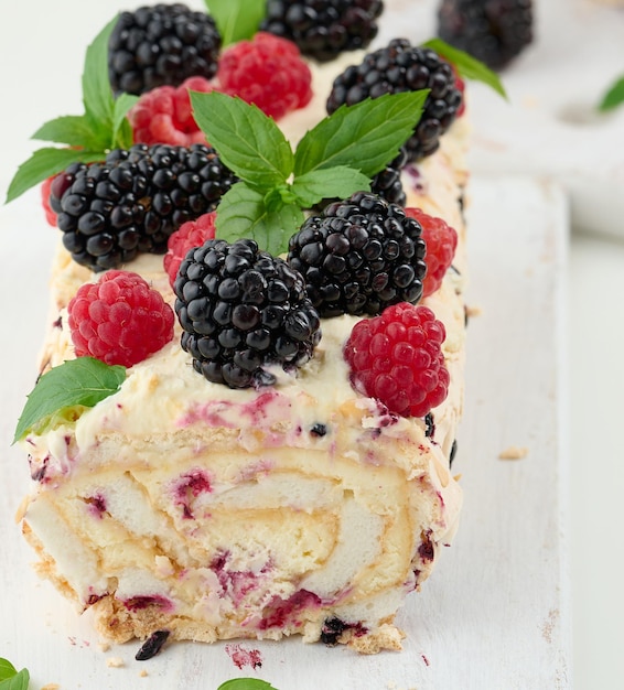 Gebakken meringuebroodje met room en vers fruit op een heerlijk dessert op een wit houten bord