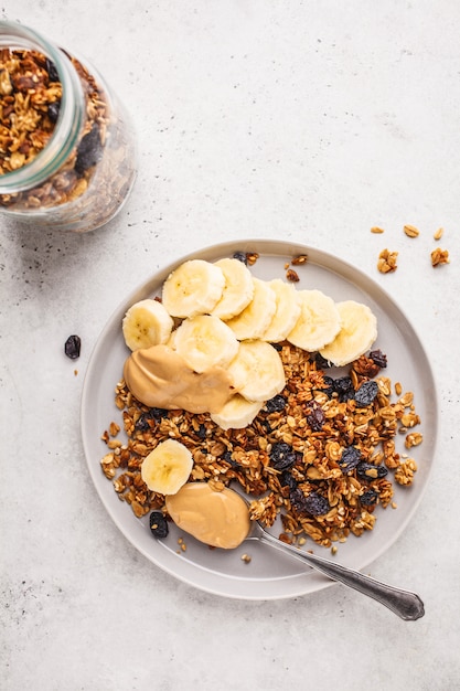 Gebakken muesli met rozijnen, banaan en pindakaas, bovenaanzicht, kopie ruimte.