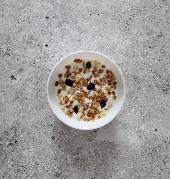 Gebakken muesli met yoghurt in een witte kom op lichte achtergrond, bovenaanzicht.