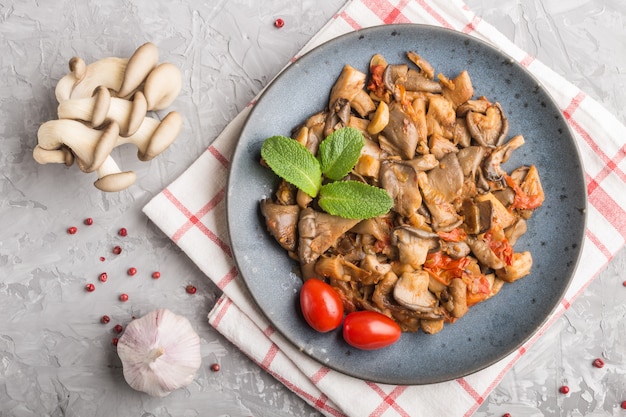 Gebakken oesterzwammen met tomaten op grijs