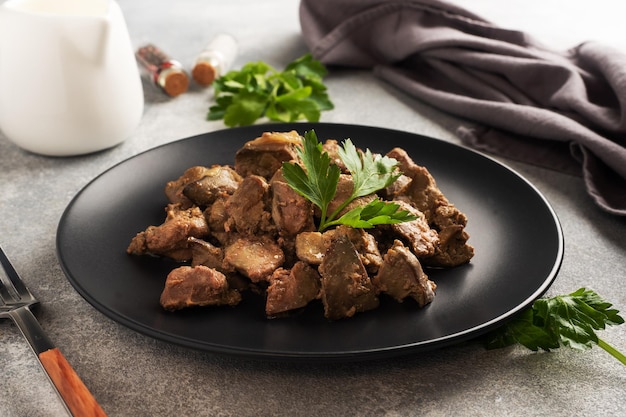 Gebakken of gebakken kippenlever met ui en saus groene peterselie bladeren op een bord Vleesgerecht verrijkt met ijzer