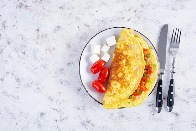 Gebakken omelet met rundvlees, tomaat, ui en kruiden. Heerlijk ontbijt met roerei. Bovenaanzicht