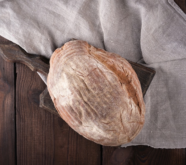 Gebakken ovaal brood gemaakt van roggemeel op een houten snijplank