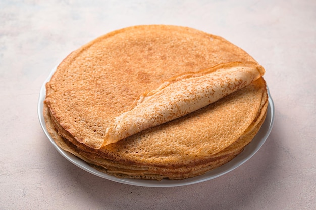 Gebakken pannenkoeken in een stapel op een lichte achtergrond. Traditionele Russische blini. Pannenkoeken dag. Zijaanzicht, close-up.