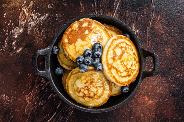 Gebakken pannenkoeken met verse bosbessen en ahornsiroop in een pan. Bovenaanzicht.