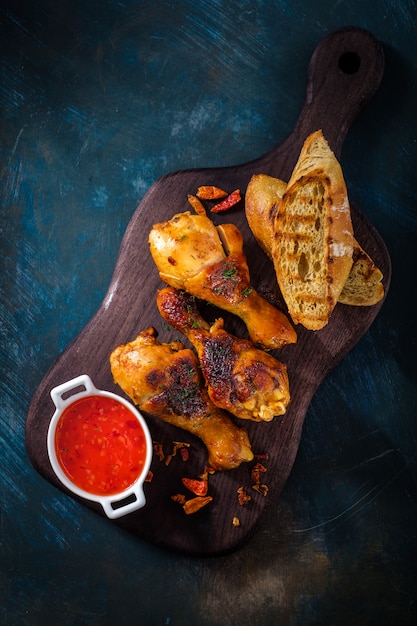 Gebakken pittige kippenpoten op het hout met de saus