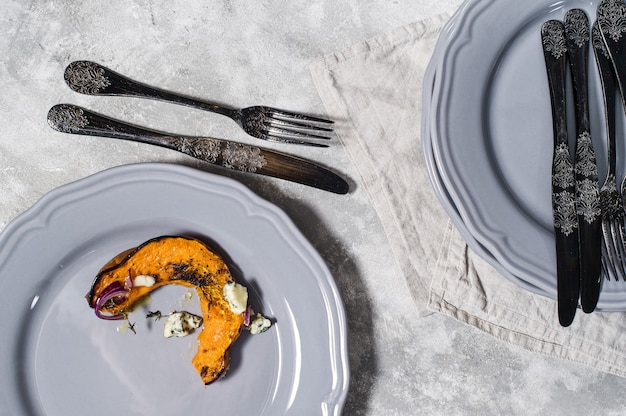 Gebakken pompoen met Gorgonzola op grijze plaat.