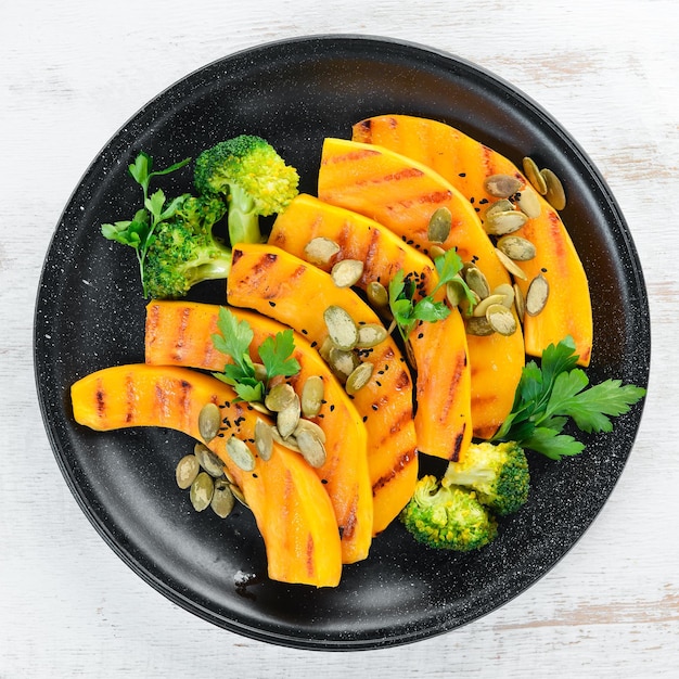 Gebakken pompoen met pompoenpitten en broccoli Op een witte houten achtergrond Bovenaanzicht Vrije ruimte voor uw tekst