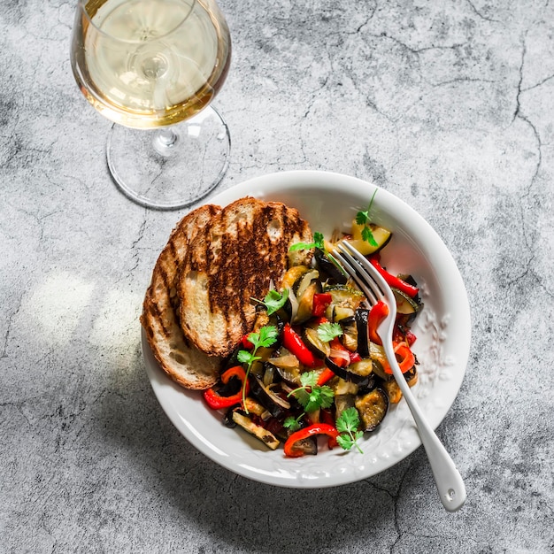 Gebakken ratatouille gegrild brood en glas wijn heerlijke vegetarische hapjes lunch snack op een grijze achtergrond bovenaanzicht