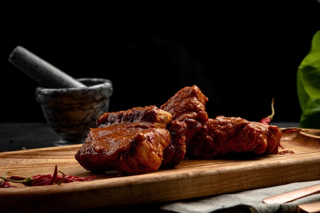 Gebakken ribben in saus geserveerd op een bord op een donkere achtergrond