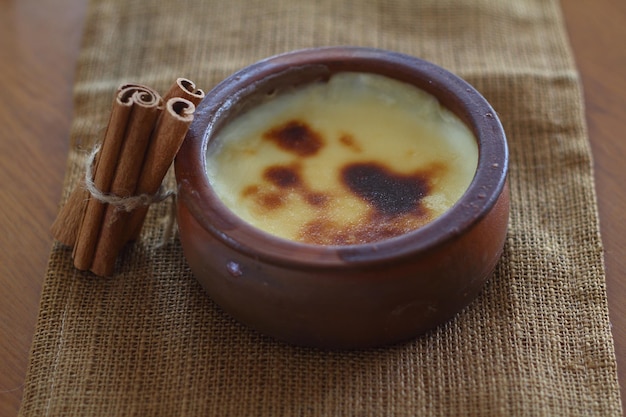 Gebakken rijstebrij Turks dessert sutlac in aardewerken braadpan met kaneelstokjes