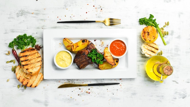 Gebakken sappige varkensribbetjes met aardappelen en saus Bovenaanzicht Op een witte plaat