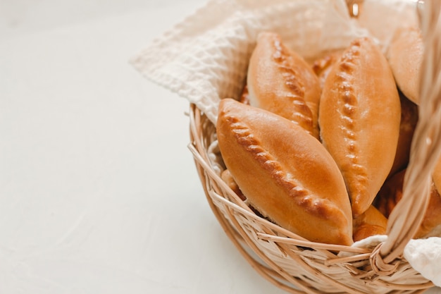 Foto gebakken taarten in een rieten mand op een witte tafel met kopieerruimte