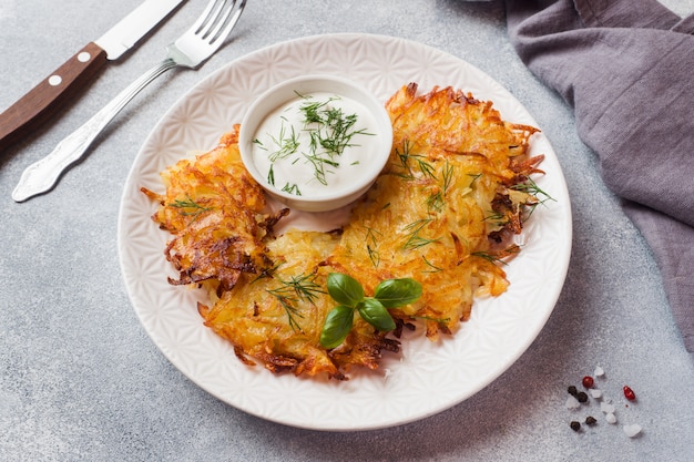 Gebakken taarten van geraspte aardappelen op het bord met saus, traditionele pannenkoeken boxty raggmunk