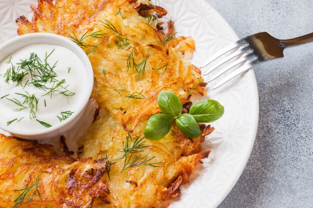 Gebakken taarten van geraspte aardappelen op het bord met saus, traditionele pannenkoeken boxty raggmunk