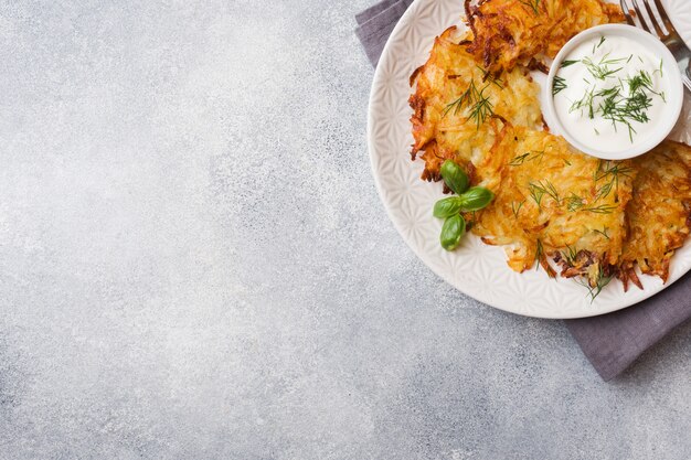 Gebakken taarten van geraspte aardappelen op het bord met saus, traditionele pannenkoeken boxty raggmunk