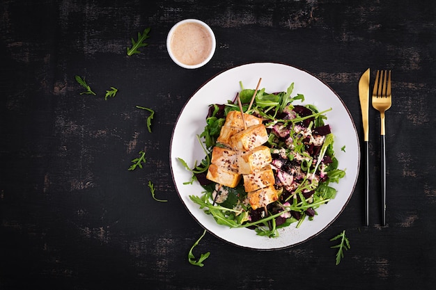 Gebakken tofuspiesjes in saus en bietensalade rucola met plantaardige yoghurtsaus gezond veganistisch voedingsconcept gezond eten bovenaanzicht plat leggen