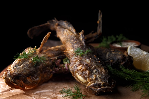 Gebakken vis grondel met saus op een houten bord