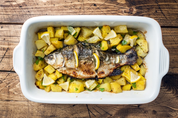 Gebakken vis karper met aardappelen in een keramische pan. Rustieke stijl.