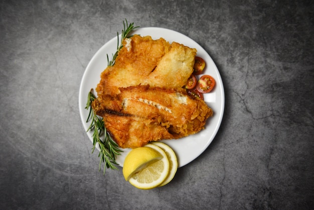 Gebakken visfilet gesneden voor biefstuk of salade koken voedsel met kruiden kruiden rozemarijn en citroen - tilapia filet krokante vis geserveerd op witte plaat en donkere achtergrond