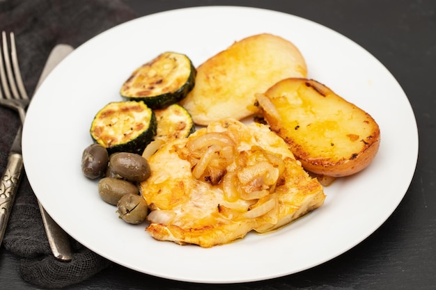 Gebakken vlees met aardappel-courgette en olijven op het bord