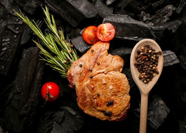 Gebakken vlees steak en cherrytomaatjes kruiden peper op een zwarte achtergrond van houtskool