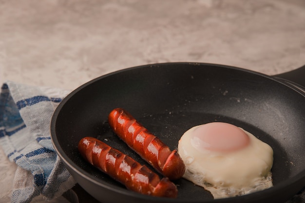 Gebakken worstjes in een pan met roerei