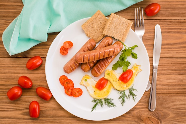 Gebakken worstjes, roerei, cherry tomaten en brood, bovenaanzicht