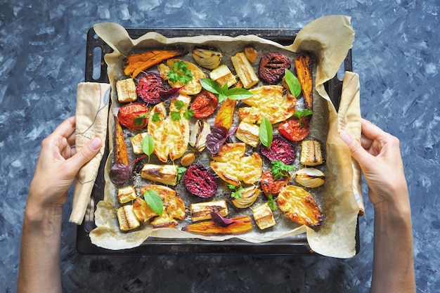 Gebakken wortelen, bieten, aardappelen, courgette en tomaten op een bakplaat, bovenaanzicht