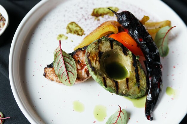 Gebakken zalmfilet met groenten en avocado op het bord van dichtbij