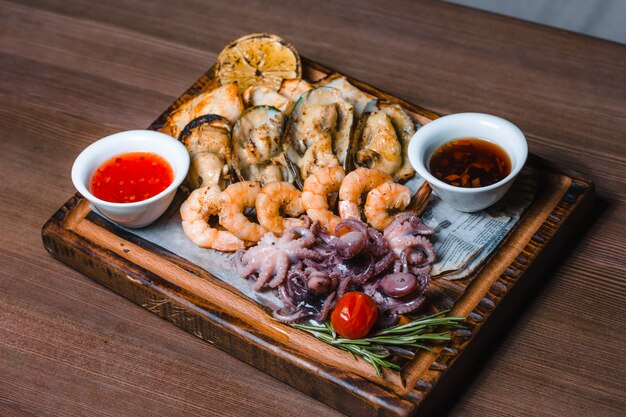 Gebakken zeevruchten inktvis, garnalen, mosselen saus op een houten bord