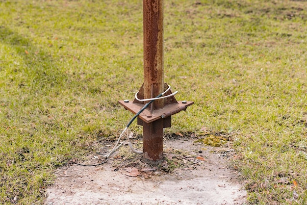 Gebarsten draad op een roestige elektriciteitspaal in het park Gevaarlijk Onveilig Kabels Veiligheidsvoorschriften Blote kabel Open Gevaarlijk Illegaal