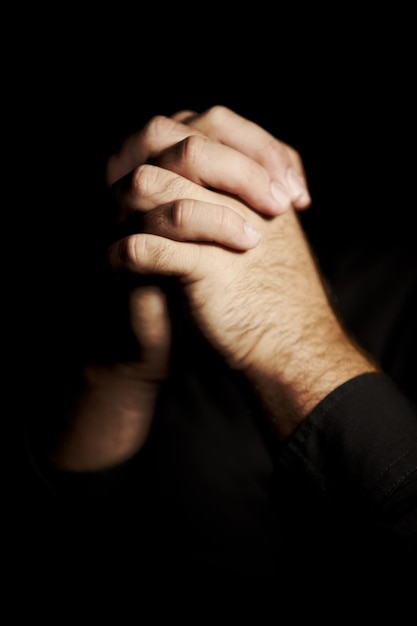 Gebed handen en zwarte achtergrond voor geloof hoop en religie of vragen om hulp met geestelijke gezondheid of ondersteuning in de studio Gebed emoji christelijke persoon en sorry vergeven of de mensheid in de donkere kamer