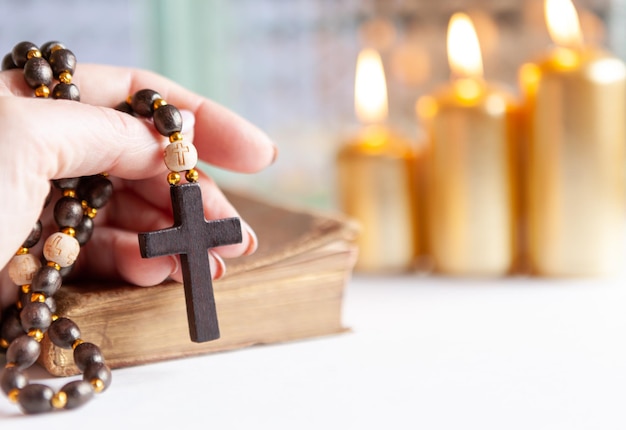 Gebedenboek en houten rozenkrans kralen met kruis in de hand