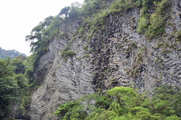 Gebeeldhouwde rots naast de berg Pailon del Diablo en waterval in de Andes Banos