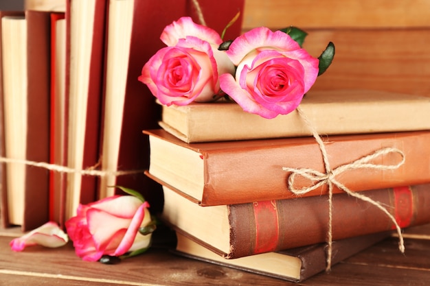 Gebonden boeken met roze rozen op houten tafel, close-up