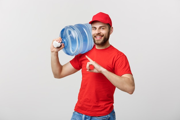 gebotteld water levering koerier in rood t-shirt en pet dragende tank drinken en wijzen