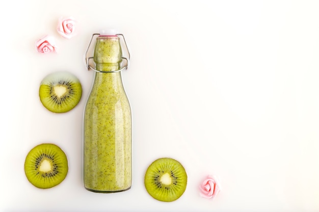 Gebottelde kiwi-smoothie met plakjes verse kiwi in een melkbad. Vegetarische, biologische, bio en detox drank. Concepten van voeding, diëtetiek, gezondheidszorg, wellness en levensstijl. Ruimte voor tekst.
