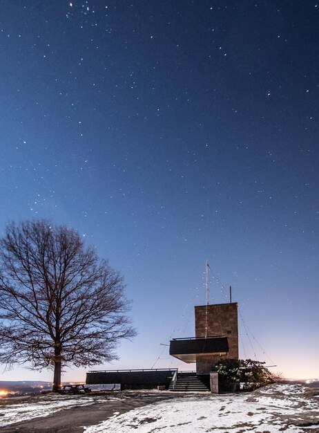 Foto gebouw en kale boom op het veld tegen de sterrenhemel